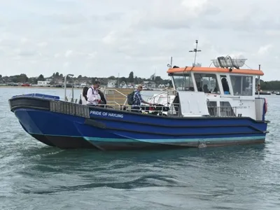 The blue and white Pride of Hayling passenger ferry under way with walkers on deck
